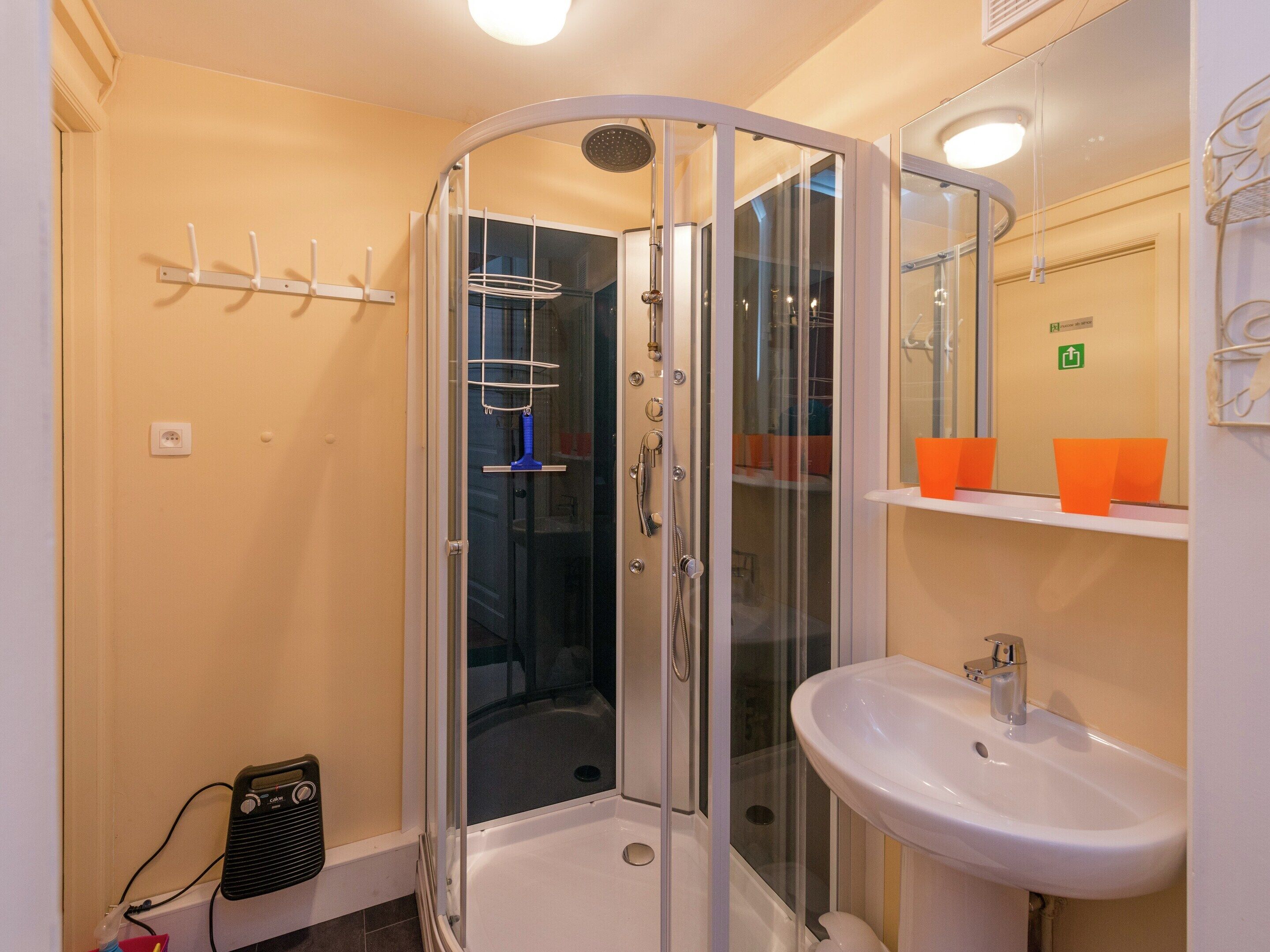 Une salle de bain avec une douche à parois de verre, un lavabo blanc et un miroir au-dessus.