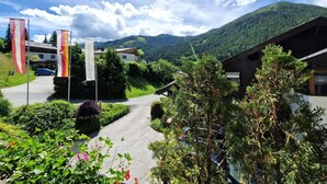 A mountain lodge with a paved driveway leading to the entrance, surrounded by lush greenery and a mountainous backdrop. - Apartment in Bad Kleinkirchheim (Bad Kleinkirchheim)