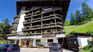 A multi-story hotel with balconies adorned with plants, a parking area, and a clear sky. - Apartment in Bad Kleinkirchheim (Bad Kleinkirchheim)