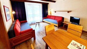 A cozy room with a sofa, a television, and a dining table. - Apartment in Bad Kleinkirchheim (Bad Kleinkirchheim)
