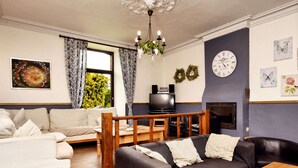Una sala de estar con un sofá, un televisor, una chimenea y un reloj en la pared.