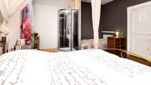 Un dormitorio con una cama grande, cabina de ducha de vidrio, mesita de noche y armario.