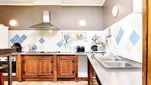Una cocina con armarios de madera, un lavamanos de acero inoxidable, un microondas y una estufa a gas.