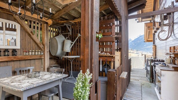 A rustic wooden interior with a dining area, kitchen, and outdoor seating.