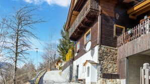 A wooden chalet with a stone facade, a balcony, and a stone wall.