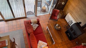 A cozy living room with a red sofa, a fireplace, and a dining area with a table and chairs. - Bungalow With View Near Coo (Stavelot)