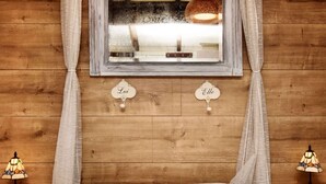 A bedroom with a wooden headboard, a window with curtains, two bedside tables with lamps, and a bed with a floral bedspread. - Bungalow With View Near Coo (Stavelot)