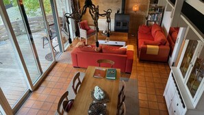 A spacious living area with a wooden floor, a red sofa, a dining table with chairs, and a fireplace. - Bungalow With View Near Coo (Stavelot)