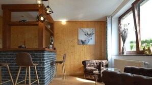 Ett mysigt rum med en bardisk i trä, en soffa i läder och ett bord i glas.