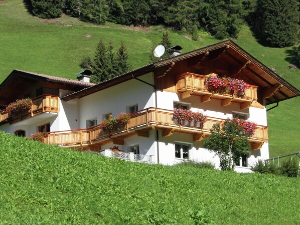 A multi-story building with wooden balconies, white walls, and a sloped roof.