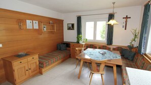 A cozy room with a wooden bench, a dining table with chairs, a small cabinet, and a window with curtains. - Cozy Apartment in Ausservillgraten (Ausservillgraten)