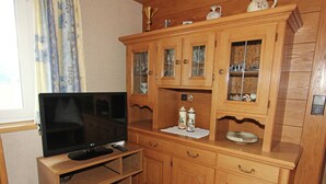 A wooden cabinet with glass doors, a television on a wooden stand, and a decorative plate on the cabinet. - Cozy Apartment in Ausservillgraten (Ausservillgraten)