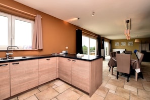 A modern kitchen with a large island, a dining area with a table and chairs, and a view of the outdoors.
