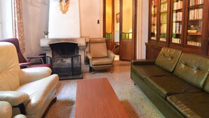 A cozy living room with a fireplace, leather armchairs, a green sofa, and a wooden bookshelf. - Family Villa in Ferrieres (Ferrieres)