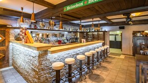 Eine Bar mit einem Heineken-Schild, einer Holztresen und mehreren Barhocker.