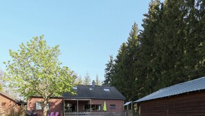 A brick house with a porch, a wooden shed, and a lawn.