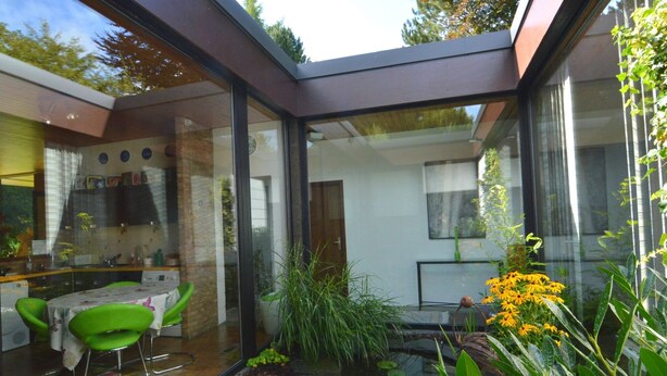 A modern kitchen with a dining area, a small pond, and a variety of plants. - Luxury Villa with Swimming Pool near F1 Circuit (Stavelot)