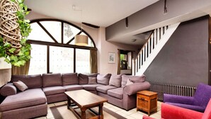 Una sala de estar moderna con un sofá modular, una mesa de centro de madera y un sillón rojo.