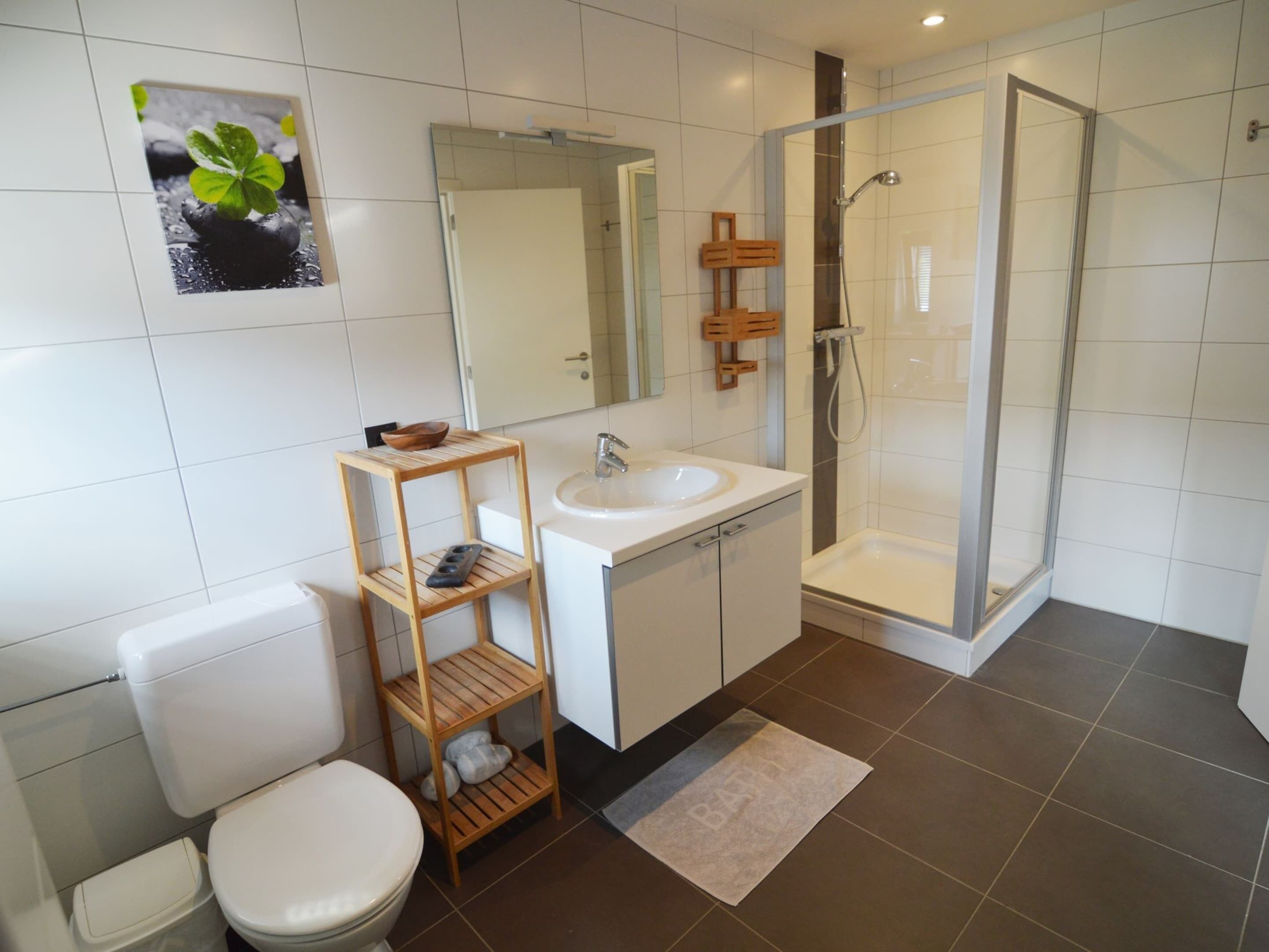 A modern bathroom with a toilet, sink, and shower.