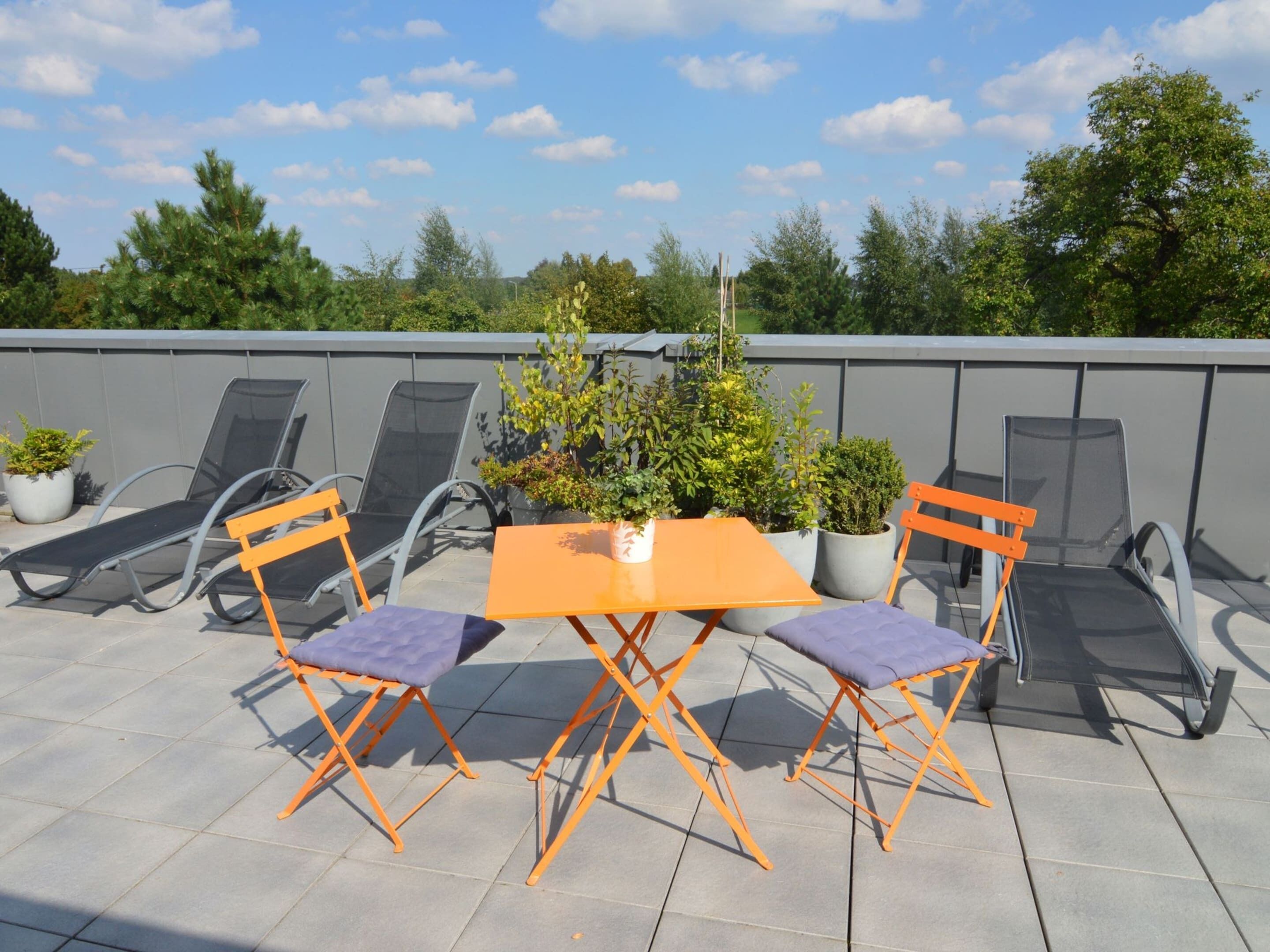 A rooftop terrace with outdoor seating and potted plants.