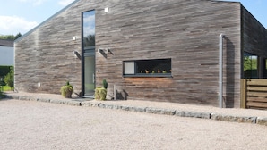 A modern building with a slatted wooden facade, a large vertical window, and a small window with plants. - Family Villa, Profondeville (Profondeville)