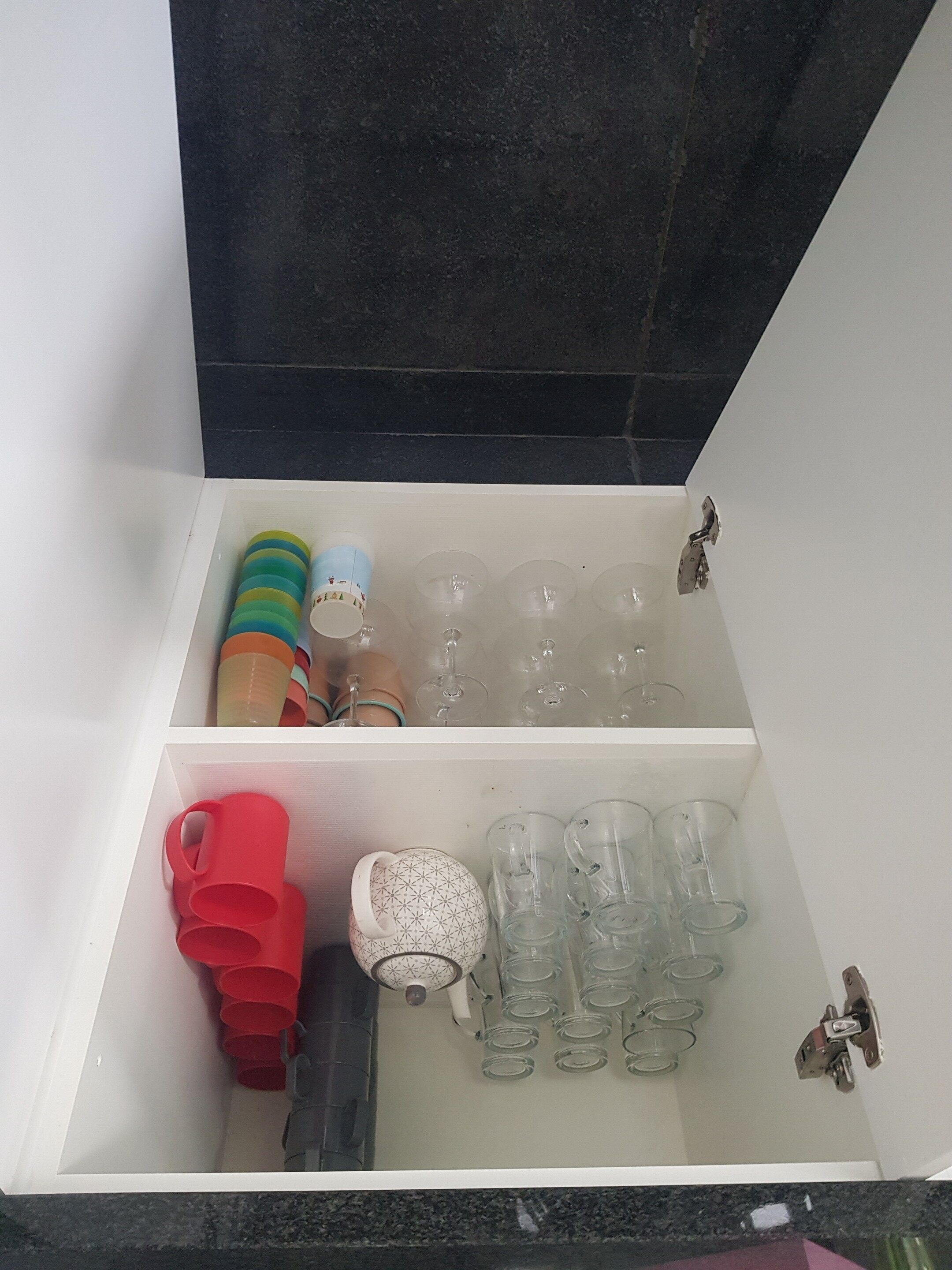 A storage unit with shelves holding various items including glass bottles, a teapot, and colorful containers.