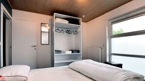 A bedroom with a bed, a wardrobe, a radiator, and a window. - Luxurious Home With Sauna (Somme-Leuze)