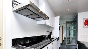 A modern kitchen with white cabinetry, a black countertop, and a stainless steel range hood. - Luxurious Home With Sauna (Somme-Leuze)