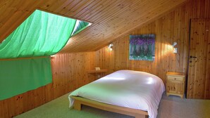 A bedroom with a sloped ceiling, a bed, a nightstand, a wall-mounted light, and a painting. - Spacious Holiday Home With Private Garden (Houyet)