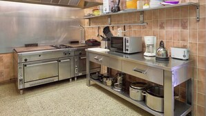A commercial kitchen with stainless steel appliances, including a stove, microwave, and coffee maker. - Spacious Holiday Home With Private Garden (Houyet)