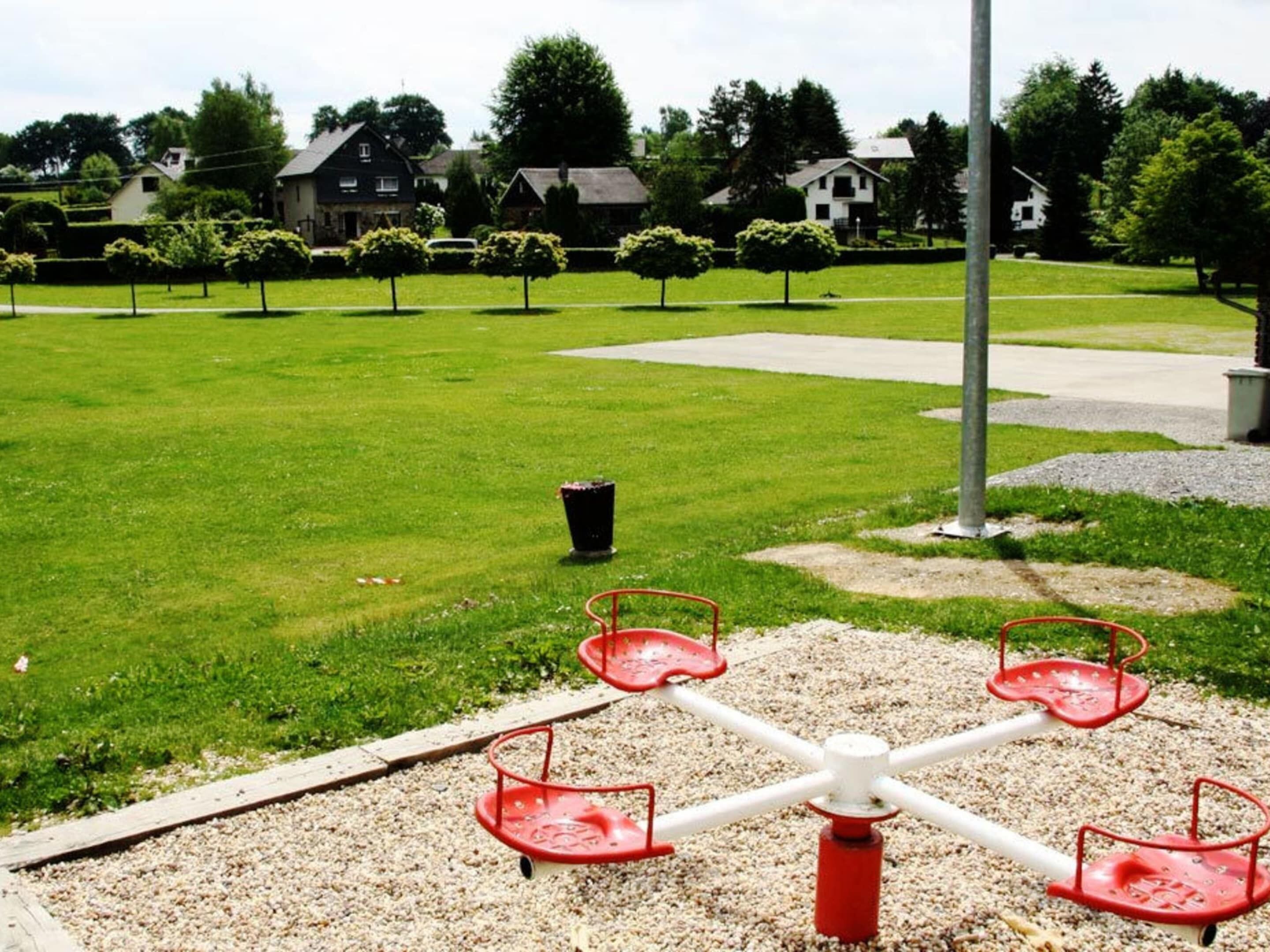 Un terrain de jeux avec une balançoire et une poubelle dans un parc.