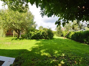 Guests can stroll through a serene garden area surrounded by trees and shrubs along a paved pathway.