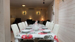 A dining area with a long table set for a meal, surrounded by white chairs. - Beautiful Apartment in Spa Belgium with Hot Tub (Spa)