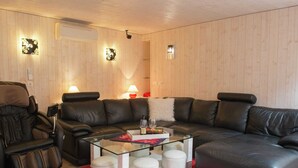 A modern living room with a leather sofa, glass coffee table, and white ottomans. - Beautiful Apartment in Spa Belgium with Hot Tub (Spa)