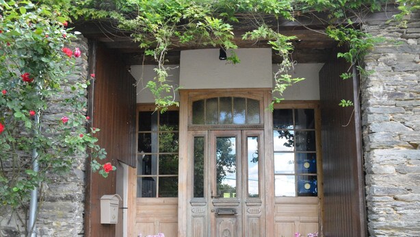 A stone building with a wooden door, large windows, and a small porch area. - House Full of Charm & Comfort, Great Calm, Large Sauna, Large Hot Tub (Bievre)
