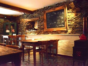 A rustic interior with a stone wall, wooden furniture, a chalkboard menu, and a vintage red kettle. - House Full of Charm & Comfort, Great Calm, Large Sauna, Large Hot Tub (Bievre)