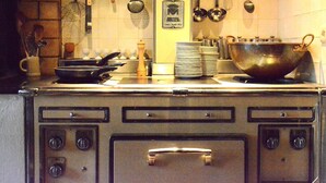 A vintage kitchen with a stove, pots, and utensils hanging on the wall. - House Full of Charm & Comfort, Great Calm, Large Sauna, Large Hot Tub (Bievre)