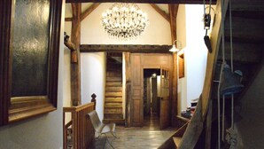 A wooden staircase with a chandelier, a chair, and a wooden bench. - House Full of Charm & Comfort, Great Calm, Large Sauna, Large Hot Tub (Bievre)