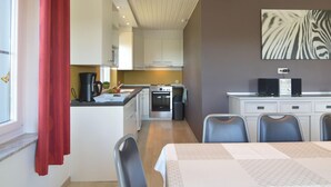 A modern kitchen with white cabinets, a dining area with a table, and a zebra print artwork on the wall. - Retreat in Malmedy Hills (Malmedy)