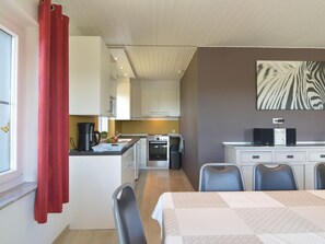 Enjoy meals in this cozy kitchen and dining area, featuring an oven, microwave, and small island with a kettle and fruit.