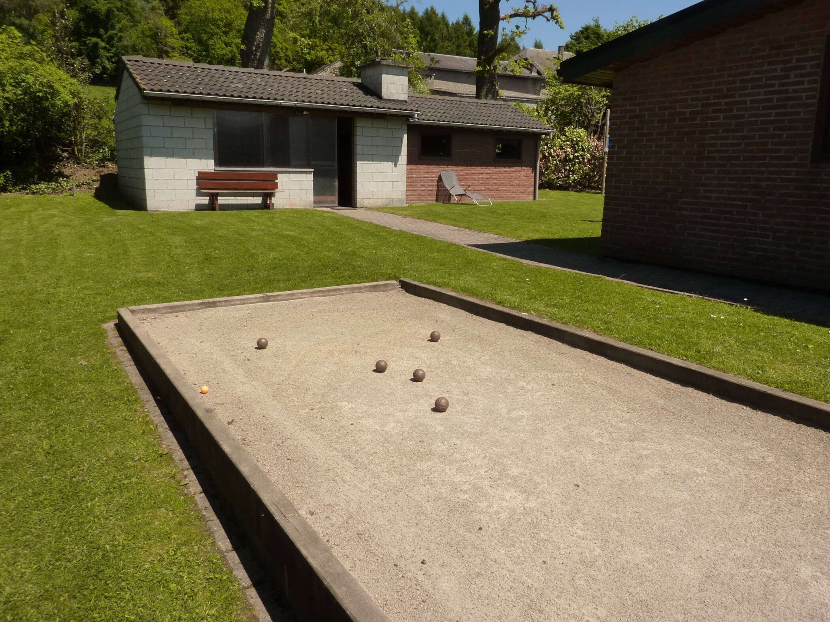 Una cancha de croquet con césped, un banco y un edificio al fondo.