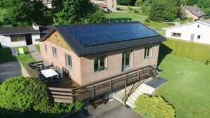 A two-story building with a solar panel roof, a wooden deck, and a covered outdoor seating area. - Retreat in Malmedy Hills (Malmedy)