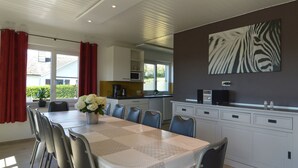 A dining area with a table set for six, a kitchen in the background, and a zebra print artwork on the wall. - Retreat in Malmedy Hills (Malmedy)