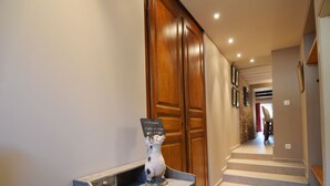A hallway with a wooden door, a small table with a ceramic pig, and a checkered bench. - Holiday Home in Ardennes Near Chimay Abbey (Viroinval)