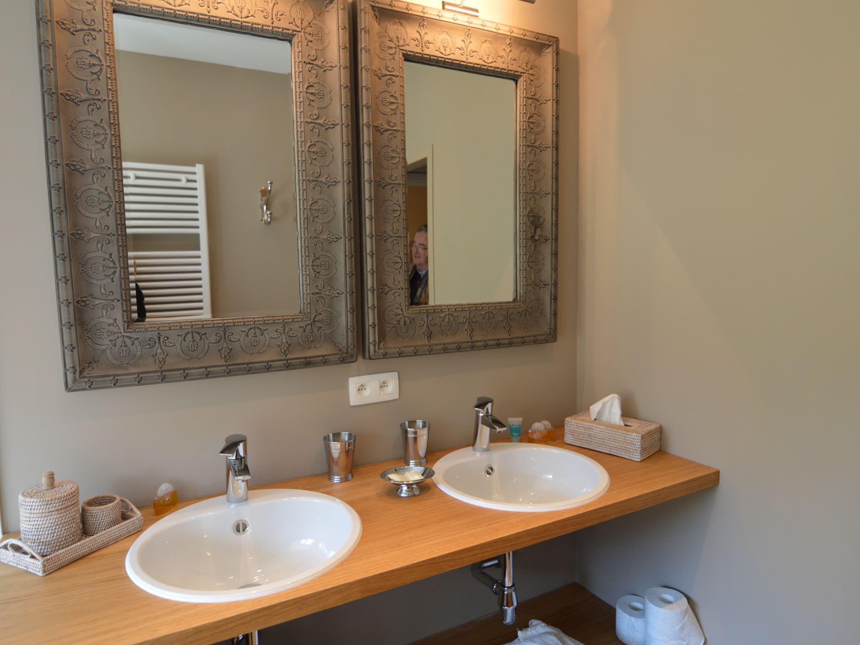 A bathroom with two sinks, a mirror, and a towel rack.