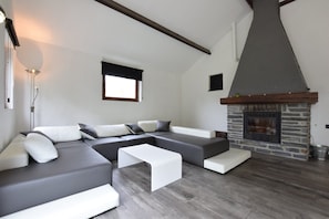 Una sala de estar moderna con un sofá modular, una chimenea y un ventanal grande.