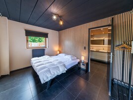 Una habitación de hotel moderna con una cama grande, una ventana, un baño con espejo y un perchero.
