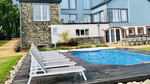 A two-story house with a stone facade, a swimming pool, and a deck with lounge chairs. - Holiday Home in Cetturu With Sauna (Houffalize)