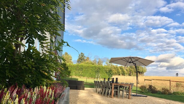 A patio area with a table and chairs, an umbrella, and a gravel path. - Holiday Home in Cetturu With Sauna (Houffalize)