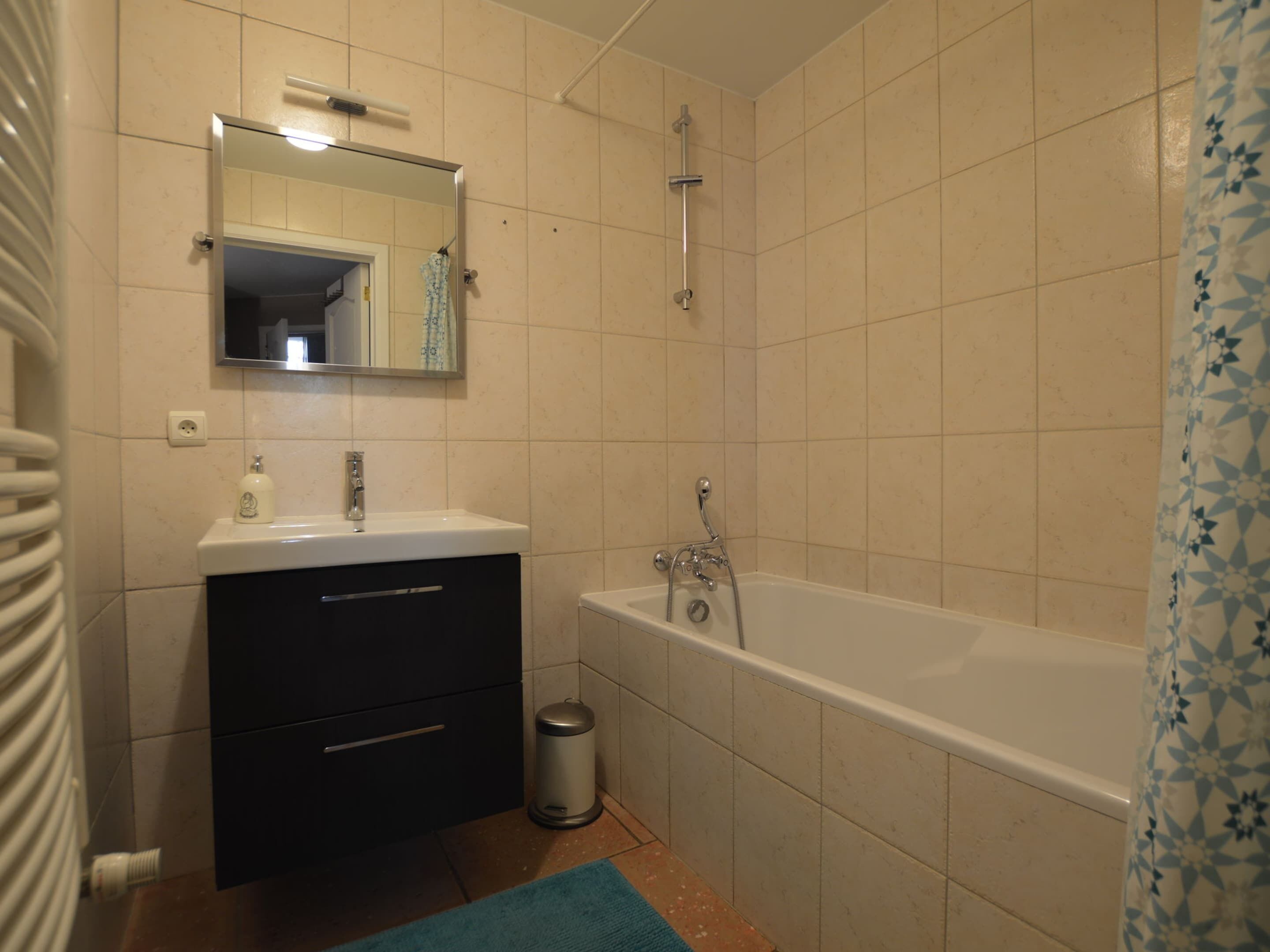 A bathroom with a sink, mirror, vanity, and bathtub.